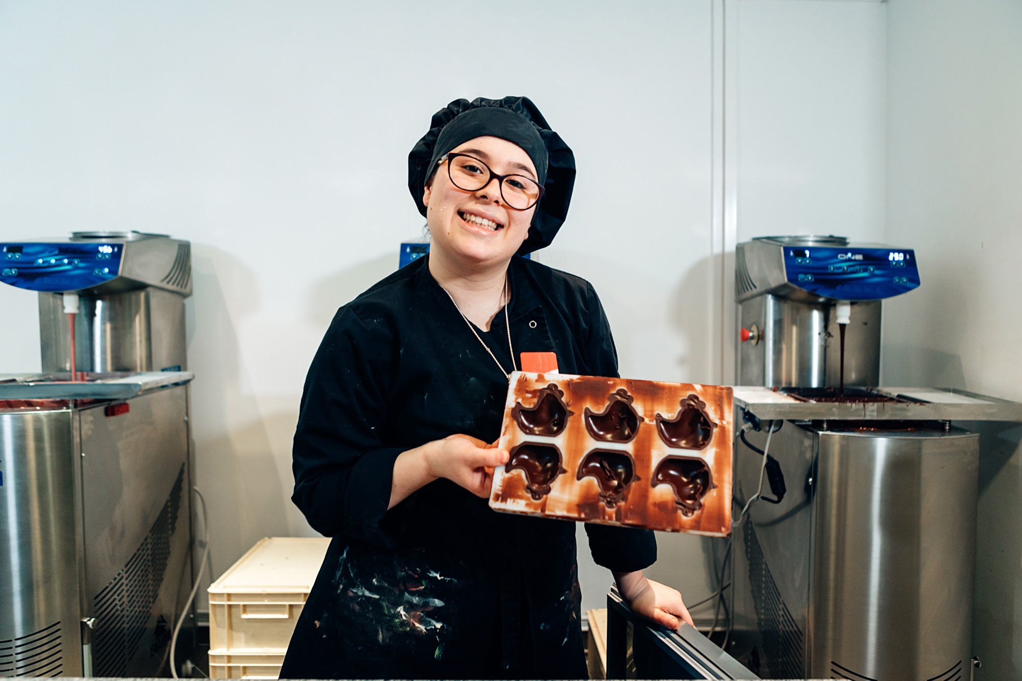 Chocolatière zeigt lächelnd eine Pralinenform